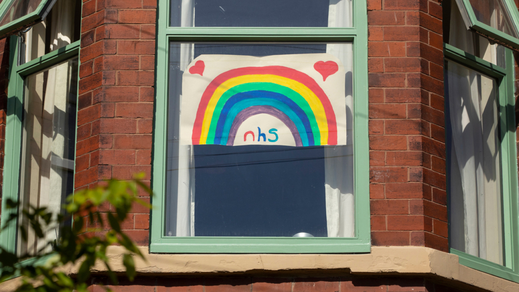 a painting of a rainbow with the word NHS written below, placed in a sunny window